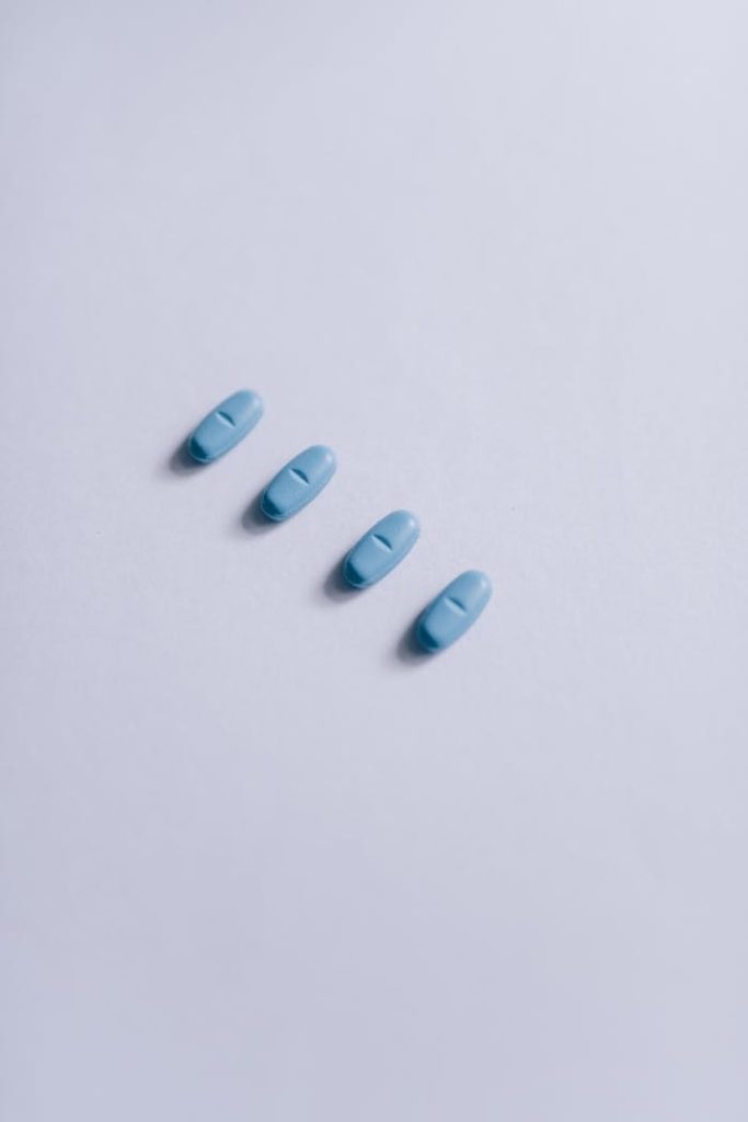 Close-up of four blue pills arranged on a clean white surface.